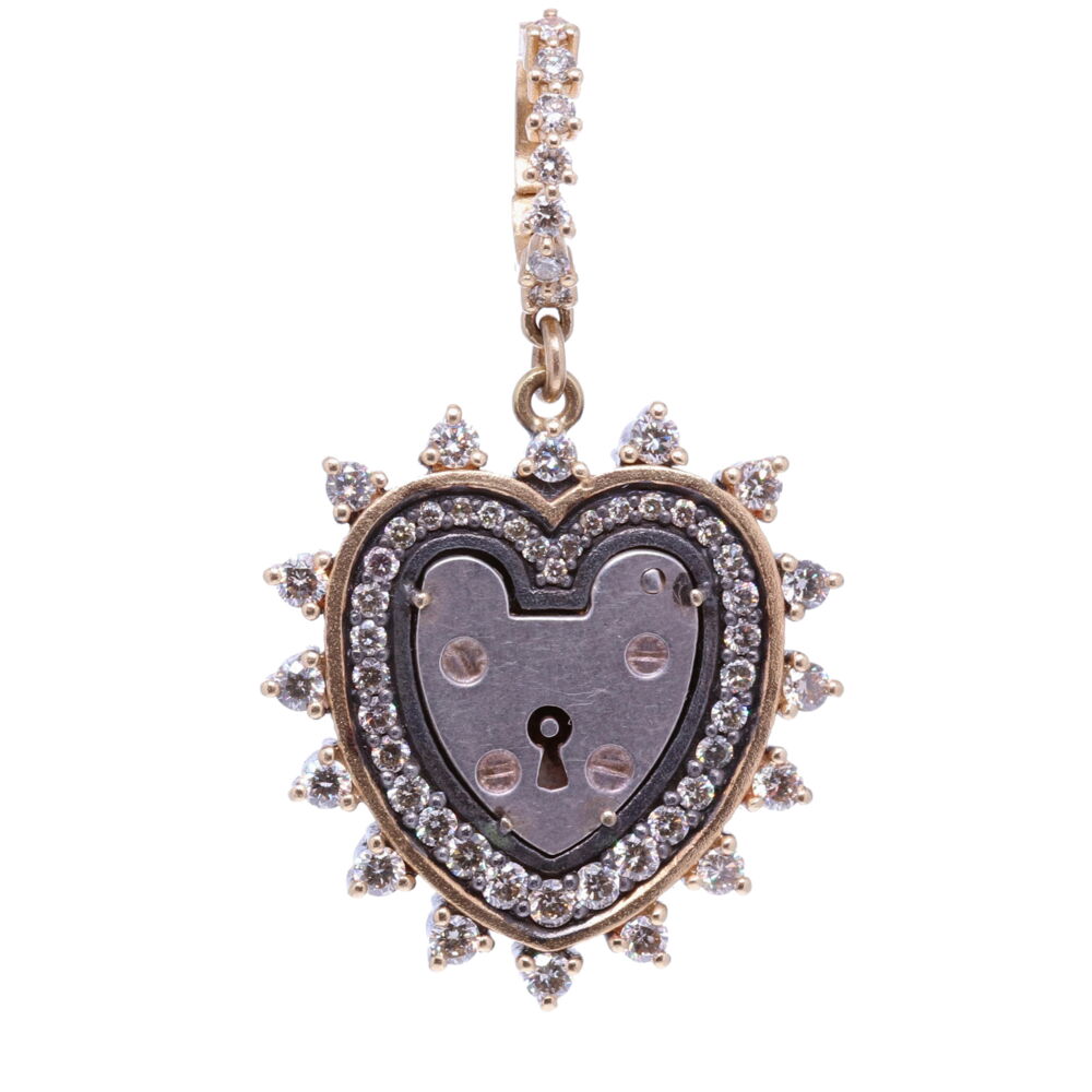 The Antique English padlock was typically worn on a bracelet and given to a loved one to show how much they were loved. Before going off to war, gentlemen would leave the bracelet locked around his loved one’s wrist and he would hold the key until his return. The heart shaped padlock was fashionable in the Victorian and Edwardian periods.
Heart Shaped Vintage Padlock, Surrounded by a Champagne Diamond, 14k Yellow Gold and Black Rhodium 3 Prong Bezel, Hanging from a Champagne Diamond and 14k Yellow Gold Openable Bale.
Champagne Diamond - 1.3tcw
14k Gold - 4.17g
Black Rhodium Silver Heart Shaped Vintage Padlock