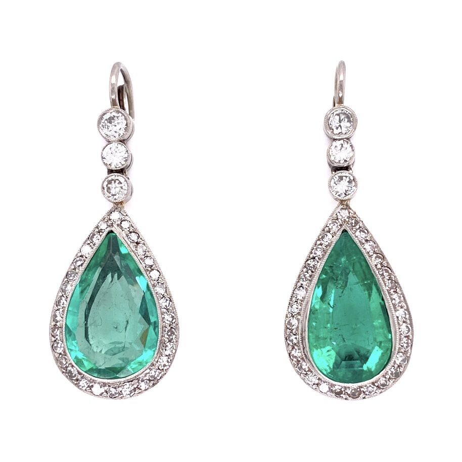 These vintage platinum earrings feature two pear shaped emeralds with a total carat weight of 9 carats. In a beautifully accented halo around these large emeralds are white diamonds, weighing a total of 1.70 carats. A wonderful heirloom that your children's children will love to see passed down. Platinum Pear Emerald & Diamond Drop Earrings