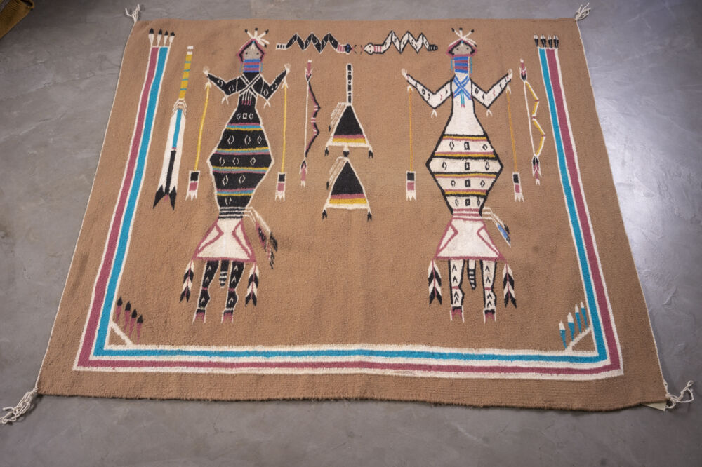 Part of Ken Johnson's collection of Navajo rugs, Yei (Sandpainting) features a tan ground with a pair of black and white human figures surmounted by a pair of black and white snakes. Rug Cn23 Yei - Sandpainting
