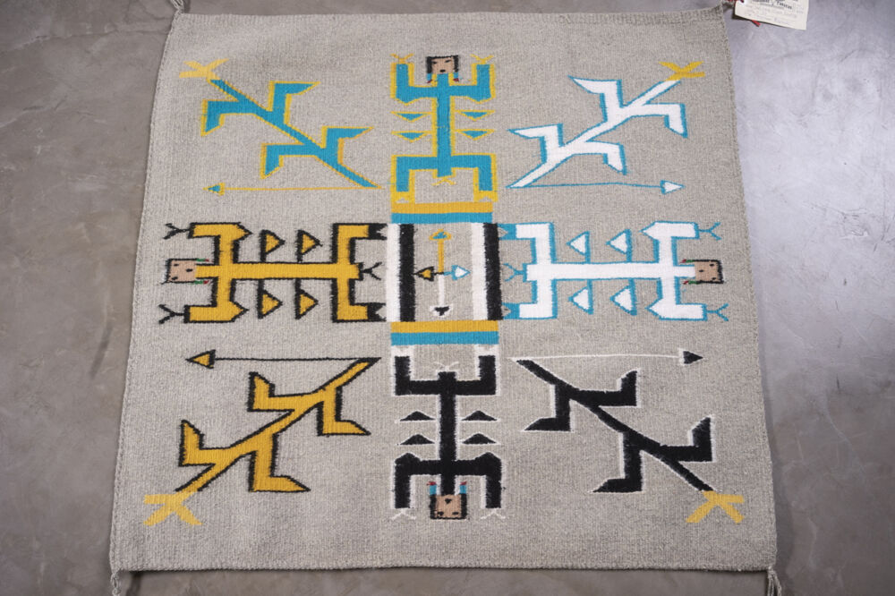 Part of Ken Johnson's collection of Navajo rugs, Yei (Sandpainting) features a grey ground with four human figures and four corn stalks in black, white, blue, yellow, orange and brown and four arrows at its center. Rug Cn24 Yei - Sandpainting