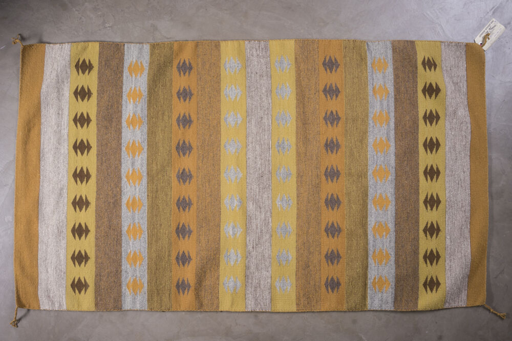 Part of Ken Johnson's collection of Navajo rugs, Crystal features a striped design in orange, grey, brown, tan and blue and a series of diamonds. Rug Cn26 Crystal
