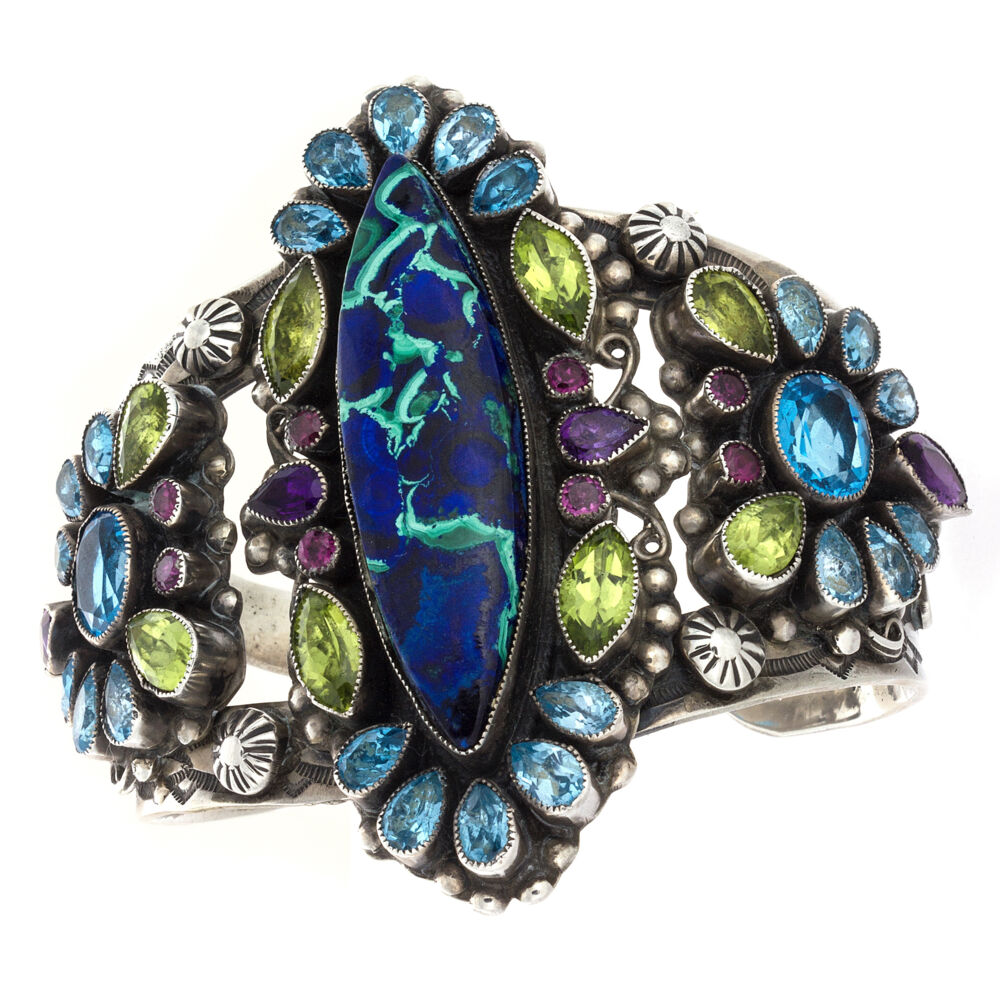 This incredibly beautiful piece is jaw dropping to say the least. The polished center stone is a mix of Azurite and Malachite. the Silver work is intense. The Leo Feeney Azurite Malachite Cuff is also abound with cut gemstones. Faceted Blue Topaz, Peridot and Amethyst put this beauty over the top! The intense color of the Leo Feeney Azurite Malachite Cuff are sure to gather plenty of compliments from anyone you cross paths with. Leo Feeney Azurite-Malachite Cuff With Peridot, Blue Topaz, Amethyst & Pink Tourmaline