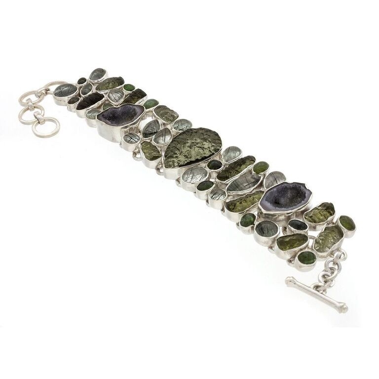 This earthy tone Moldavite bracelet includes many gemstones off-setting the unique texture of the cosmic-origin glass. The assortment includes mini druze geodes, green tourmaline cabochons and tourmalated quartz cabochons all placed in a fluid sterling silver cagework setting with toggle clasp. Moldavite Bracelet With Tourmaline, Tourmalated Quartz & Geodes