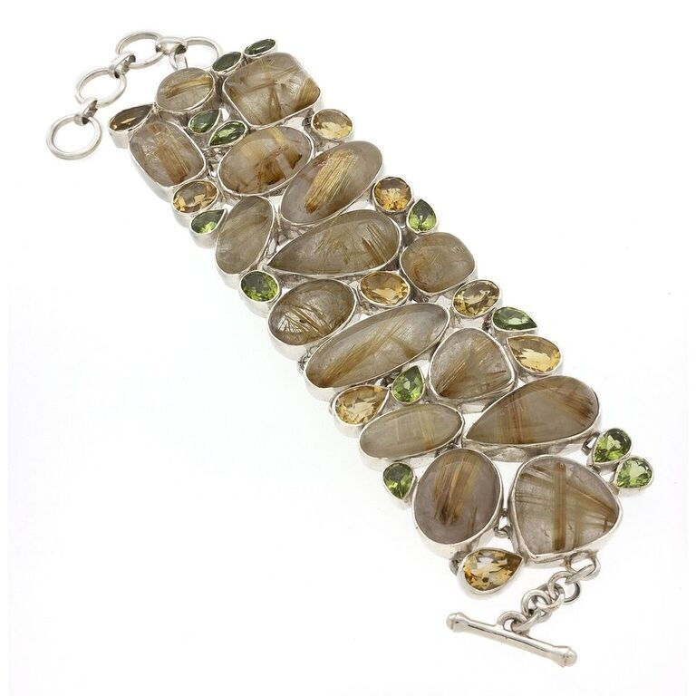 Fifteen hand polished, various shaped cabochons of rich Golden Rutile Quartz accented by sparkling faceted peridot and citrine. Bezel set and piece linked to the adjacent gems the composition of this bracelet is substantial and second to none! Class up a casual look or wear it with boots and a blazer, the vibrant colors make it a year-round wear! Minimum length of 7.75", maximum lenth of 8.5". Golden Rutile Bracelet With Peridot & Citrine