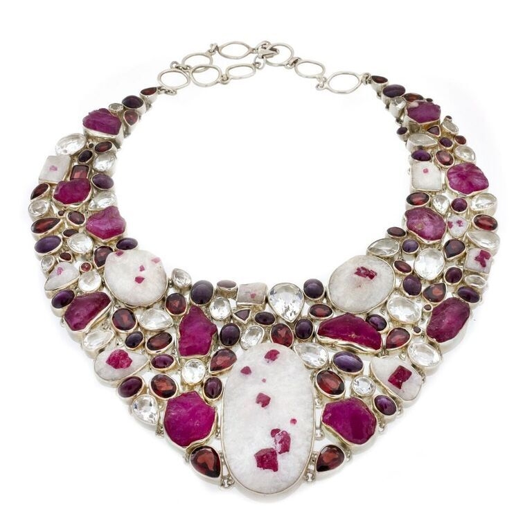 <font size="4">Dramatic bib-style necklace features rough rubies erupting out of quartz matrix, showcased by enormous, rough strawberry-red rubies, brilliant faceted quartz, faceted pomegranate-red garnets and eye-catching star-ruby polished cabochons all bezel set in .925 Sterling Silver. Each bezel set gem is linked to the adjacent bezel, allowing it to contour your unique shape, and comfortably distributing the weight of such a substantial statement piece. Large, round, sterling-silver links allow for adjustable length making it comfortable to wear. An extra-large lobster clasp makes it easy to put on and take off, not that you will ever want to! Your set is complete with dangle-style earrings of bezel set rough rubies in quartz, star-ruby cabochons on substantial sterling silver hook. This set is a head-turner!</font> Ruby Collar Necklace Rough In Matrix (Set)