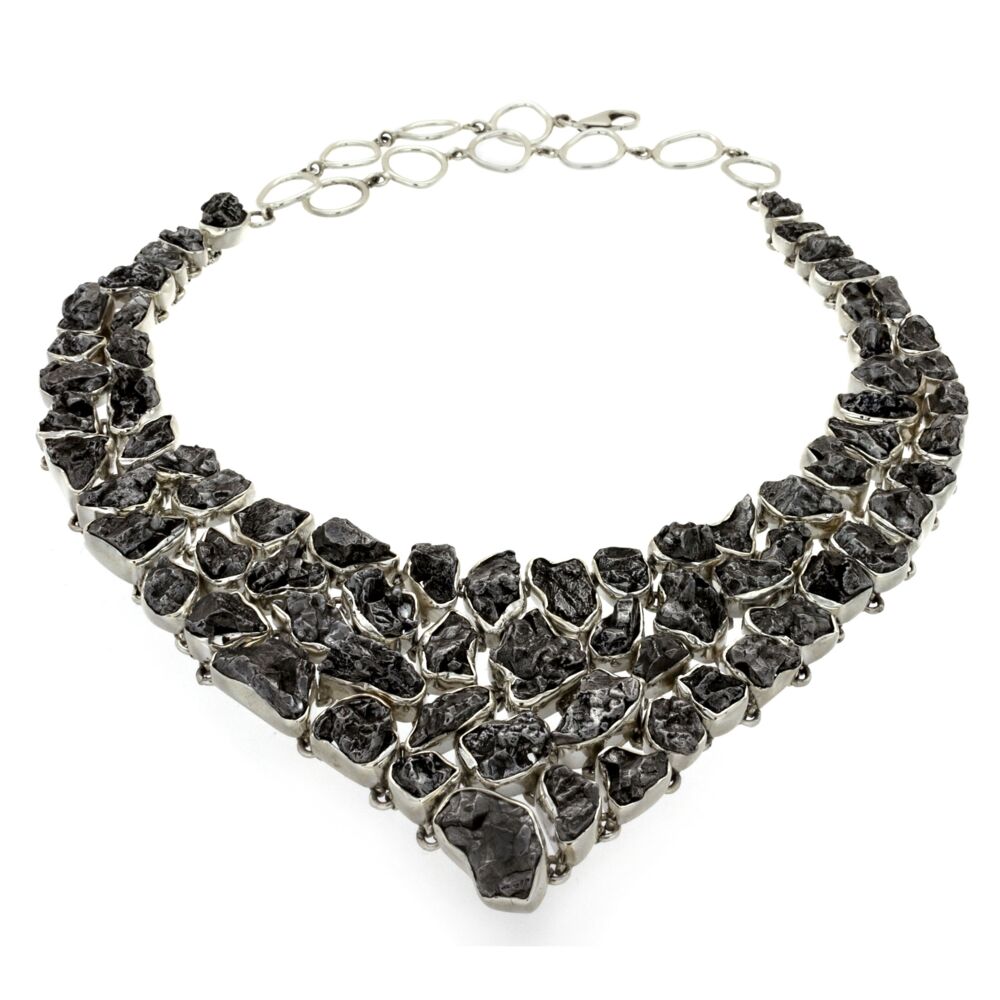 Feel your inner super-powers spark to life when donning this breathtaking Campo di Cielo meteorite, bib-style necklace. Each of the 70 out-of-this-world nuggets are individually bezel wrapped in bright .925 sterling silver and piece linked to the adjacent meteorites, allowing it to contour to your unique shape. Large oval links allow for adjustable length and comfortable wear. An extra-large lobster clasp makes it easy to put on and it's eye catching quality will make it hard to take off! Campo De Cielo Meteorite Necklace