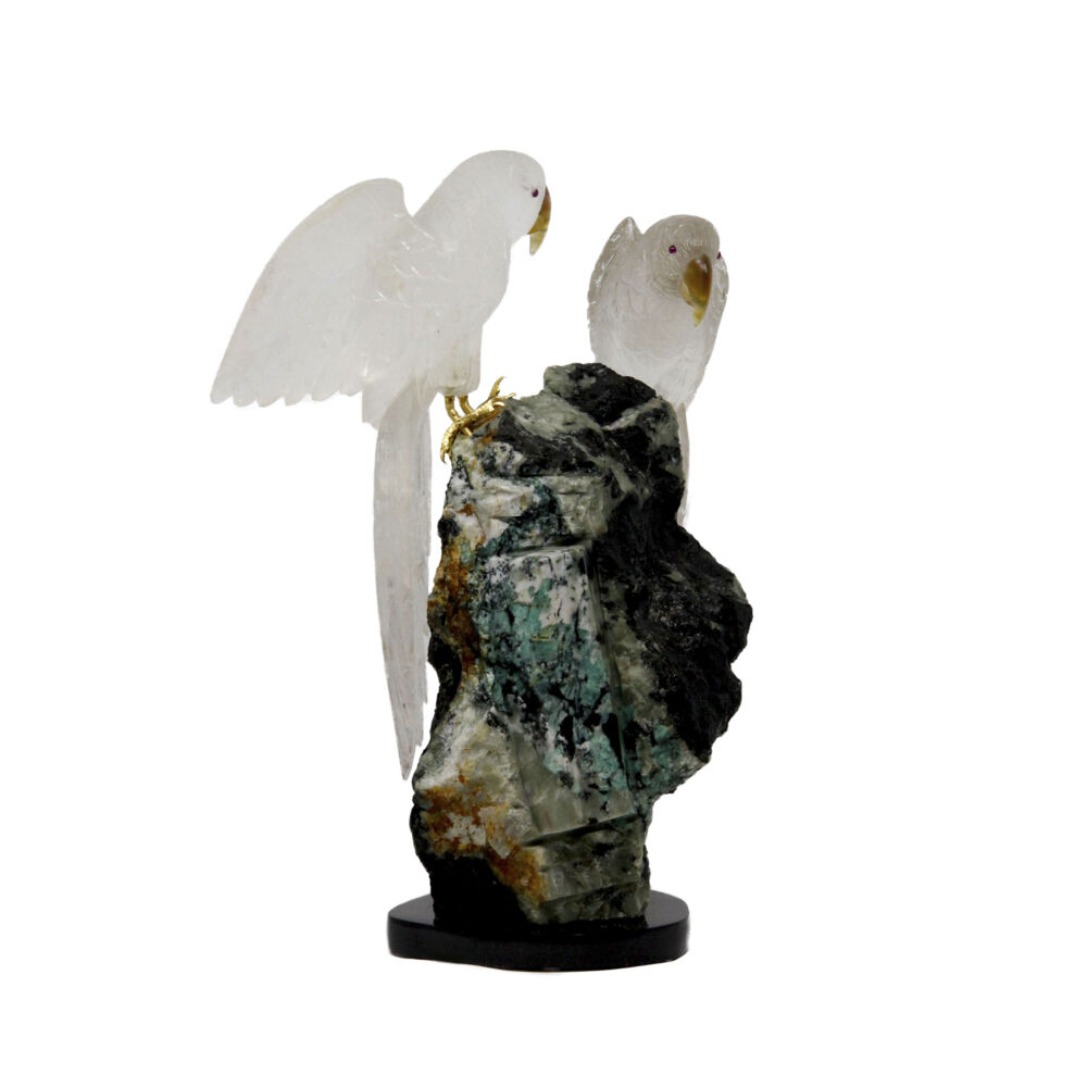 <span></span><span style="font-family: Quicksand;">Hand-carved quartz parrots sit perched atop a matrix boulder with emerald crystals. The finite details conveyed in the carved quartz parrots, with little carved citrine beaks, is astounding. The translucency of the carved quartz parrots is the perfect artistic contrast to the substantial and grounding shape and colors of the emerald in matrix. This will make a statement in any setting.</span> Clear Quartz Parrot Duo On Emerald & Matrix Boulder