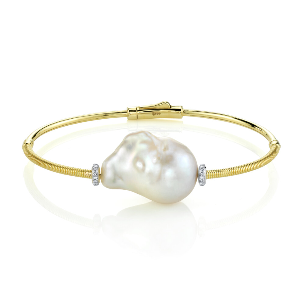 BEAUTIFUL AND EASY TO WEAR WHITE PEARL AND DIAMOND BANGLE BRACELET IN 18K YELLOW GOLD WITH SINGLE UNIQUE BAROQUE PEARL SET OFF BY TWO SHIMMERING PAVE DIAMOND ROUNDELS WITH STRIE DOUBLE HINGE WITH EASY TO CLOSE CLASP. WEAR EVERY DAY OR DRESS IT UP FOR A MORE FORMAL LOOK. Single Baroque Pearl Bangle With Diamonds