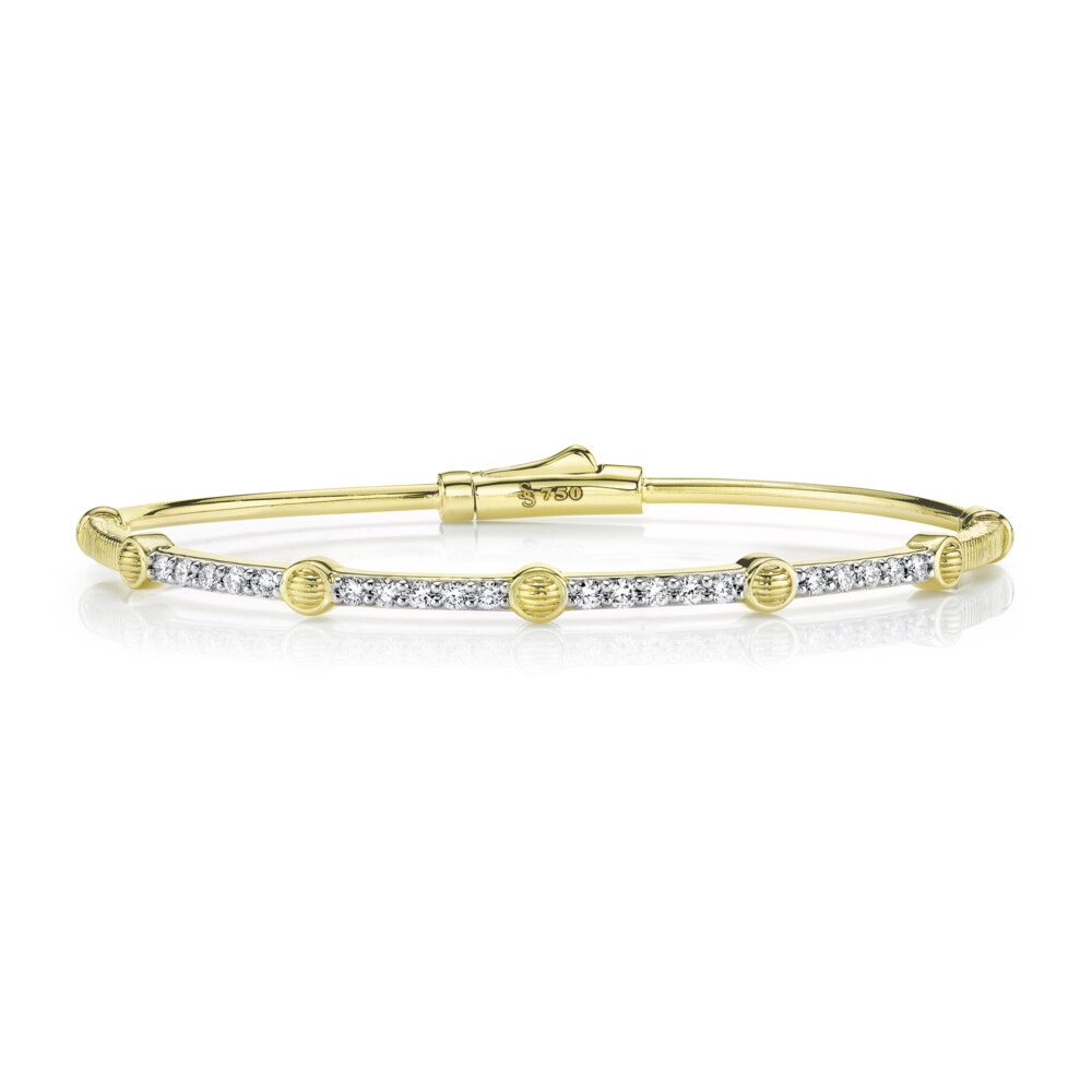 THIS TIMELESS SLOANE STREET BANGLE BRACELET IN 18K YELLOW GOLD FEATURES FIVE ROUND STRIE TEXTURED STATIONS THAT LINE THE TOP OF THE BRACELET SEPARATED BY AN ALLURING PAVE OF TWENTY SPARKLING WHITE DIAMONDS WITH DOUBLE HINGE AND HIDDEN LOCKING CLASP. THIS FUN STACKING BRACELET IS A UNIQUE TWIST ON A CLASSIC STYLE. Pave Diamond Skinny Bangle With Strie Stations
