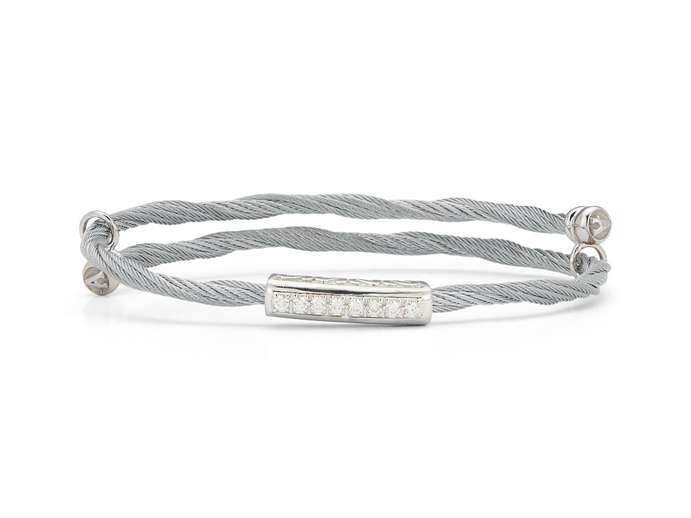 The beautifully created twisted heat treated grey colored steel cable winds around the wrist in a perfect fashion. The single long station is created from 18 karat white gold in a bar shape that is lined with a total diamond weight of .18cts. The strands are connected loosely with two stainless steel connectors. Perfect for a daily favorite or for all your special wear occasions. Look great without breaking the bank with this bangle.
Grey cable, 18 karat White Gold, 0.18 total carat weight Diamonds and stainless steel. Imported. Adjustable Single Long Station Bangle