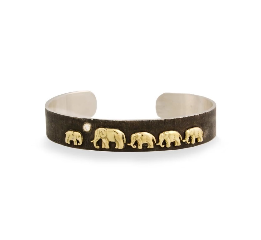 The Silver Tsavo Nights Trail Cuff is a smaller take on our best selling Tsavo Nights Cuff. The story of an orphaned baby elephant being adopted by a new herd and returning to the wild is proudly displayed in 18K gold on a platform of oxidized silver. Ten percent of profits go to The David Sheldrick Wildlife Trust to support their program of rehabilitation for elephants. Silver Tsavo Nights Trail Cuff