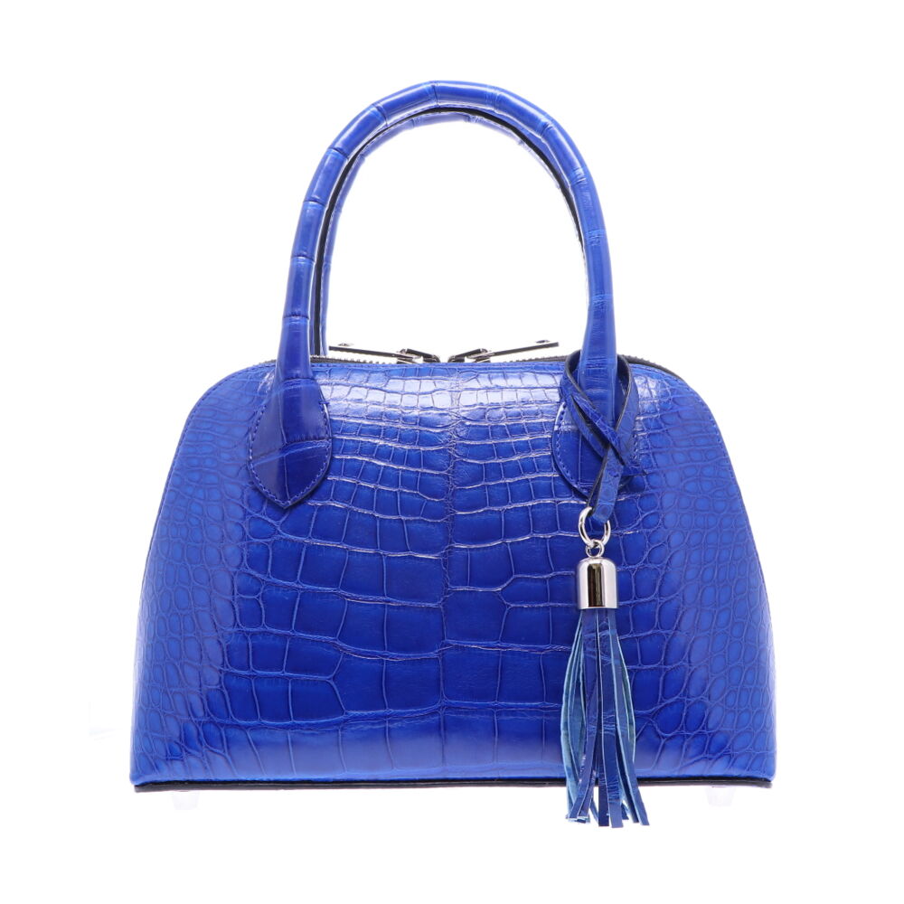 LaNae’s Small Dome is a top handle bag made of genuine American Alligator Skin. Proudly handcrafted in the USA by 3rd generation artisans, all edges are hand painted, interior is garment suede and is detailed with Italian palladium hardware. This classic style comes with a fun tassel that can be detached. The interior has a zippered and a cell phone pocket. Under the handles are D rings to attach the over the shoulder strap (up to 25”). Each luxury bag is one of a kind and especially made for you to stand out against the crowd!
Electric Blue Alligator Dome - Small