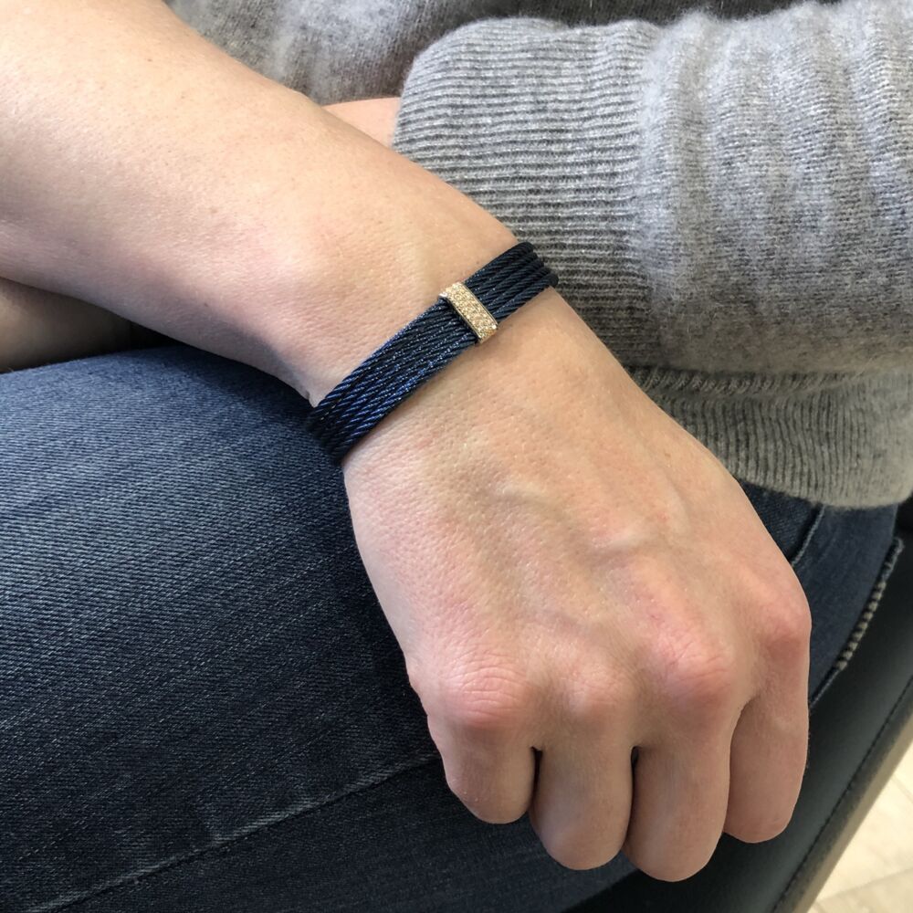 <span style="font-size: 16.8px; position: initial; margin: initial;">This beautiful blueberry heat treated steel cable cuff features five strands of cable displaying an 18k white gold diamond bar setting, with a total carat weight of .19 carats. This simple yet elegant cuff will make any day an affair.</span> Blueberry Stacked Cuff