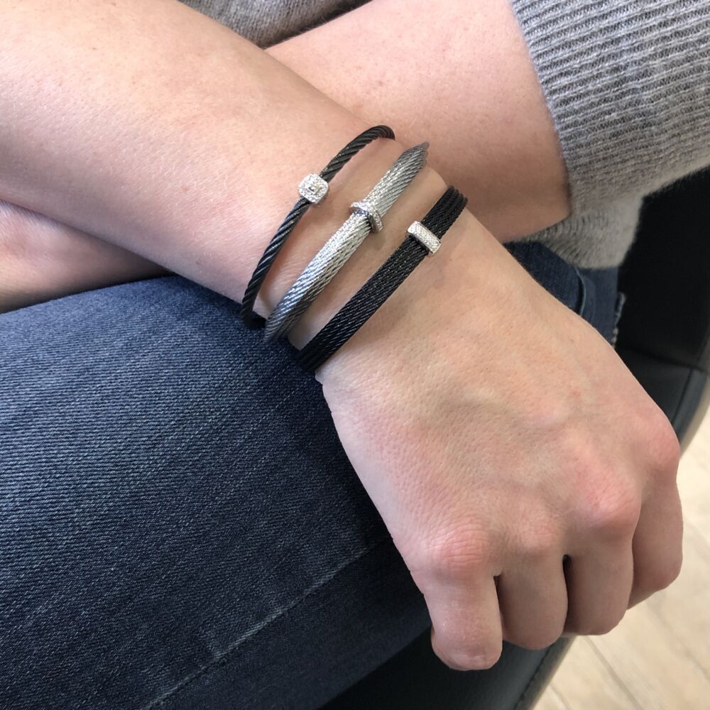 This noir heat treated steel cable features four strands of cable fused together, with an 18k white gold diamond station displaying a total carat weight of .05 carats. This bangle is perfect stacked with others, or create a simple elegance and wear it alone. Noir Four Strand Layered Bangle