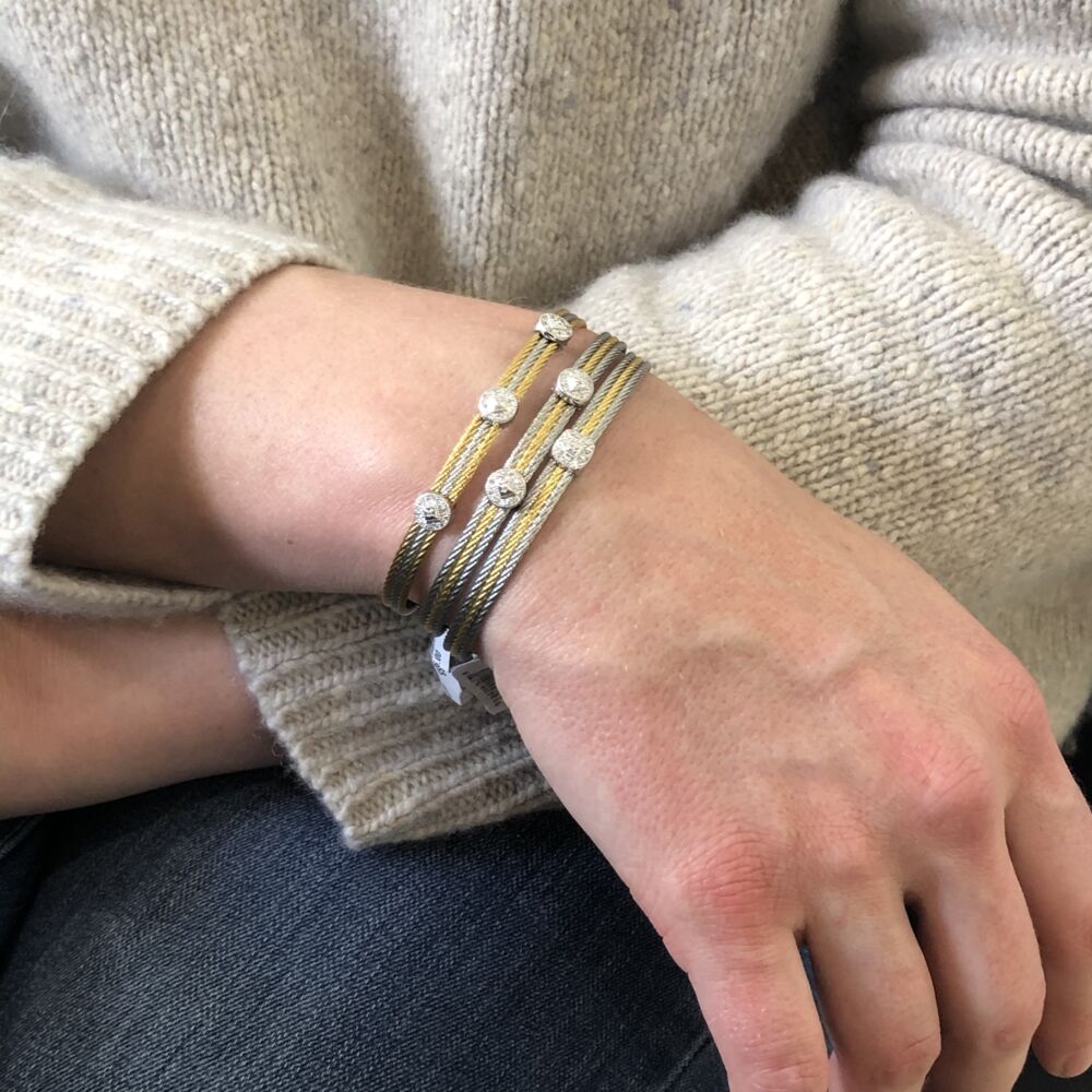This heat treated grey and yellow steel cable features two grey cables with a yellow in between. Displaying a single squared 18k white gold diamond station with a total carat weight of .05cts. This bangle is perfect to stack with others, or to just wear alone. Two Tone Single Squared Station Bangle