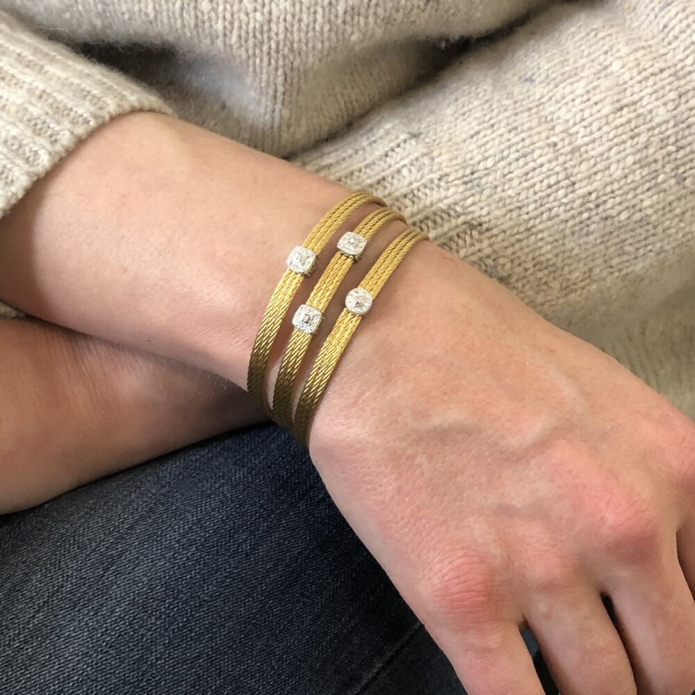This heat treated yellow colored steel cable features a single squared 18k white gold diamond station. With a total carat weight of .05 carats this bangle is perfect to stack with others or to just wear alone for a simple elegance. Yellow Single Station Bangle